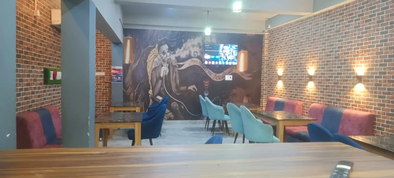 The café with brick walls, a large painted mural, teal and navy velvet chairs and pink-and-blue booth seats